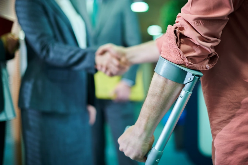 A person with a crutch holding a hand, seeking assistance from a personal injury lawyer.